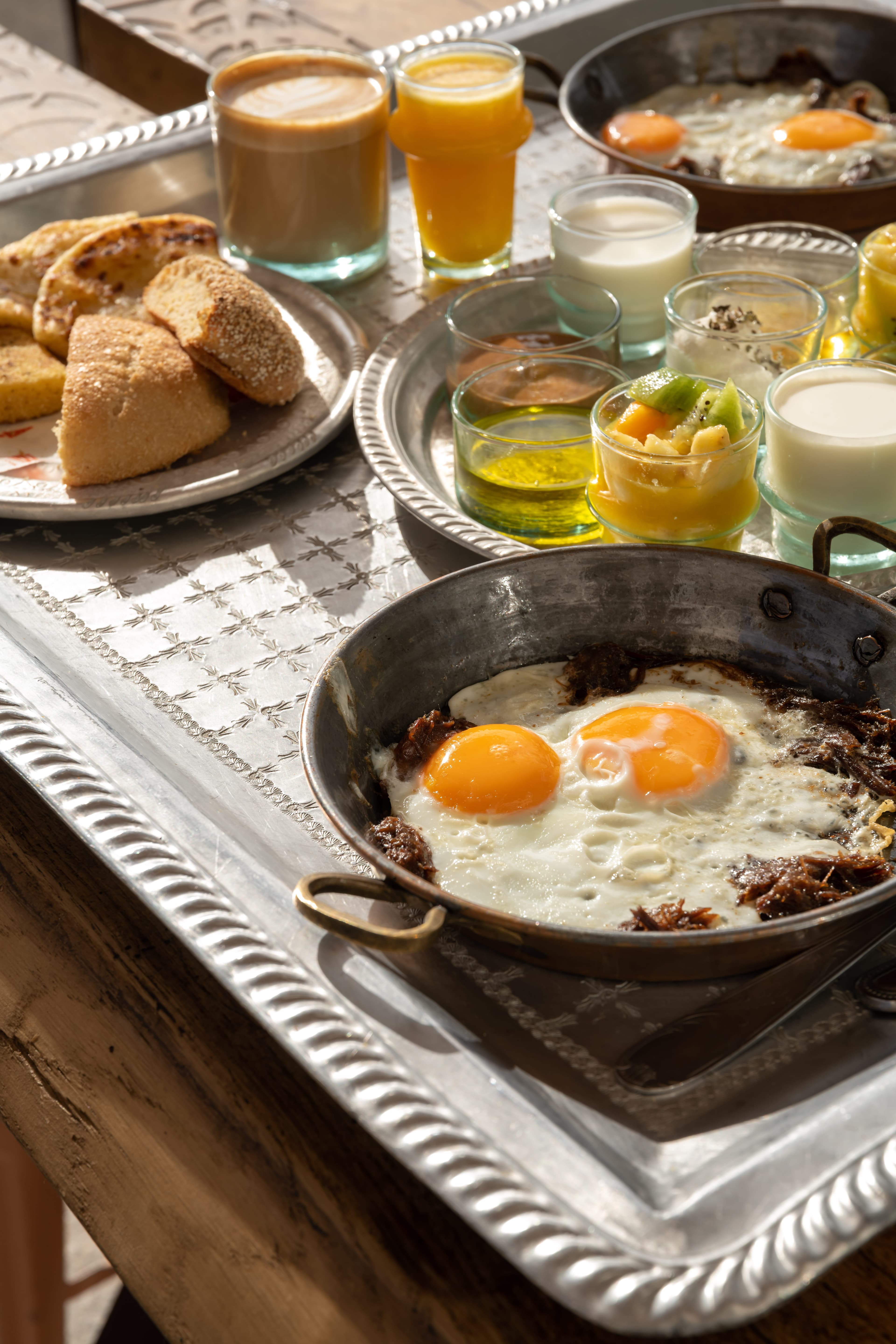 Petit-déjeuner marocain Moojood : œufs au plat, msemen, jus d'orange et café.