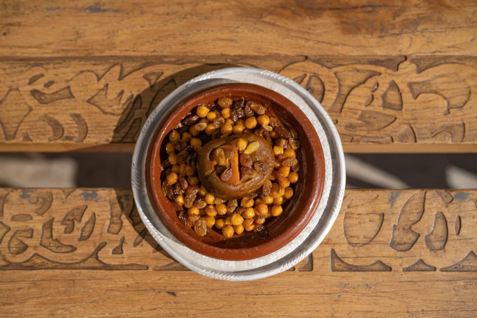 Tagine top view on carved wooden table, morning light.